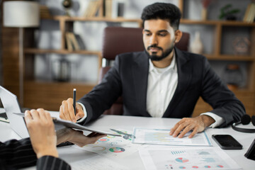 Focused young businessman signing agreement with skilled female lawyer. Concentrated financial...