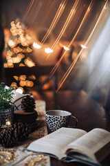 book and cup on a dark table with glittering lights background