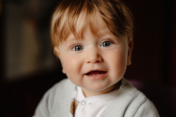 Cute baby looking into camera and laughing, showing two teeth