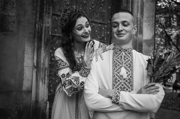 Black and white photo, young, emotional, happy couple in love, family, hugging, in Ukrainian embroidered shirts against the background of the old city. Young people hug in the old town of Lviv 