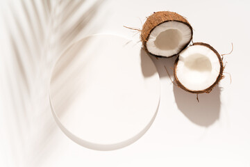 Cosmetic product design, product presentation scene made with white circle mockup podium and coconuts. Sunny background. Top view.