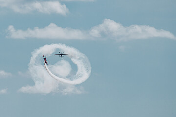 two small planes fly, pirouetting in the air and leaving white trails of smoke over a beautiful blue sky. concept of skill and dexterity. © Karlos Garciapons