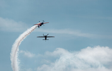 Fototapeta na wymiar two planes cross dangerously in the blue sky, leaving a trail of white smoke. danger concept