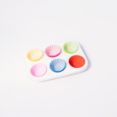 Colorful cupcake liners in a baking pan, Christmas dessert inspired creative layout, white background. 