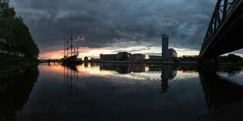 sunset at the river Weser in Bremen with reflection of the office buildings of the Überseestadt