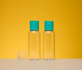 Transparent plastic bottles for liquid cosmetics on a yellow background