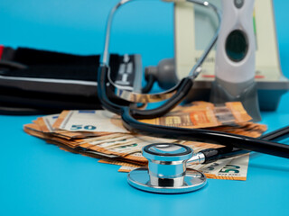 Medical stethoscope, thermometer and banknotes on a blue background.