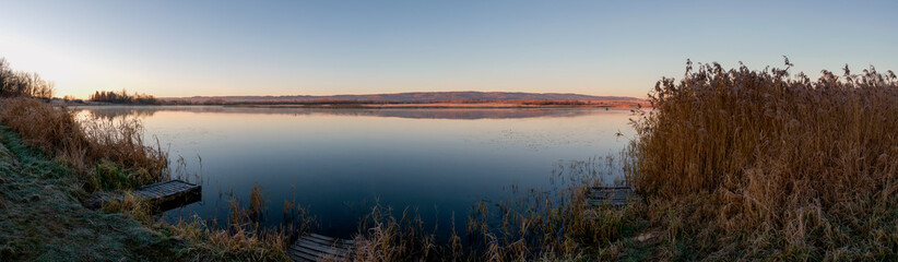 Panorama of autumn lake. Mirror reflection in water, blue sky.