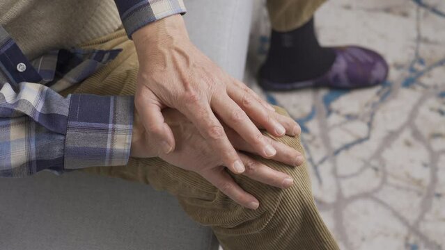 Stressed old man at home is worried.
Elderly man sitting on sofa at home rubbing hands stressed and worrying

