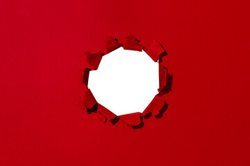Small hole in red paper, empty space for advertising text in torn paper, background texture