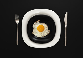 Fried eggs on a black and white plate with serving at a black table