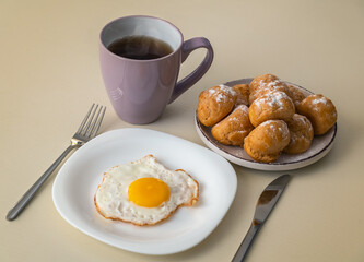 Breakfast with fried eggs, a cup of tea and profiteroles