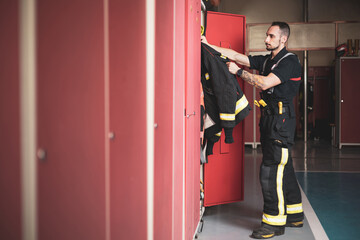 A young firefighter picking up his uniform at the locker room of the fire station.
