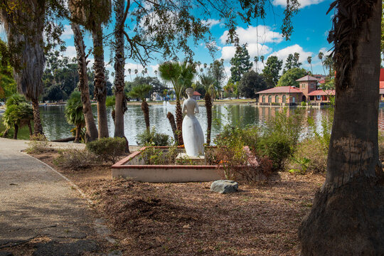 a gorgeous autumn landscape in the park with a Florence Nightingale Statue on the banks of a lake surrounded by lush green trees and grass at Lincoln Park in Los Angeles California USA