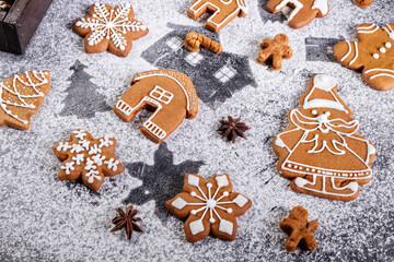 Various christmas gingerbread cookies on dark table with flour