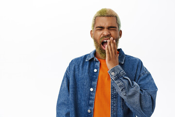 Close up of african american man yawns, looks sleepy and tired, stands over white background