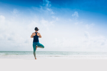 Caucasian woman practicing yoga at seashore