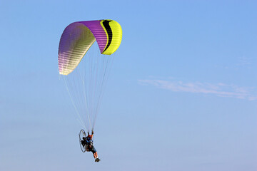 Paramotor pilot flying in a blue sky	