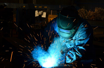 Workers wearing industrial uniforms and Welded Iron Mask at Steel welding plants, industrial safety first	