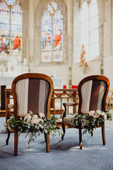 Les chaises des mariés décorés de fleurs pour la cérémonie religieuse