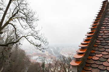 Top view of the city with red tiled roofs on a rainy foggy day, Austria, Graz