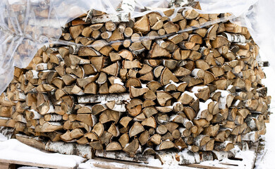 Chopped stack of firewood under snow. Preparation of firewood for the winter. Chopped stock of firewood under snow. Piles of snow covered firewood at cold winter day