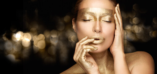 Sensual woman with glowing metallic gold makeup. Christmas woman with luxury golden body art....