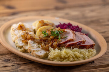 smoked meat served with red and white cabbage and two kinds of dumplings