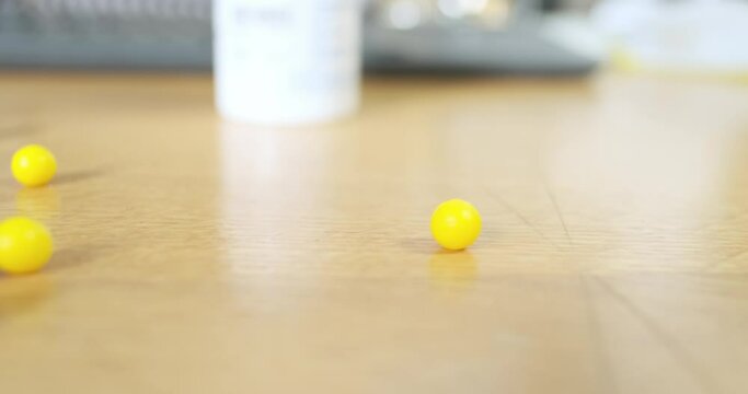 Yellow round pills are scattered on a wooden desktop. Close-up. The concept of overwork, beriberi, fatigue at work, overexertion.