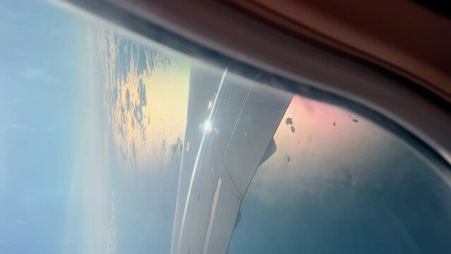 Vertical footage through illuminator of the wing of the Scandinavian airlines aircraft when landing in clear sunny weather, clouds, islands in the sea