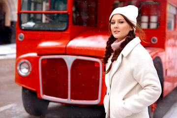 woman near London double decker red old bus in winter, walking in city in holidays