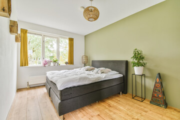 a bedroom with a bed, lamp and plants in the window simng it's bright green walls