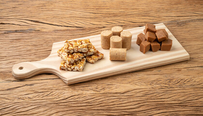 Typical brazilian candies over wooden board. Doce de leite or dulce de leche, pe de moleque and pacoca
