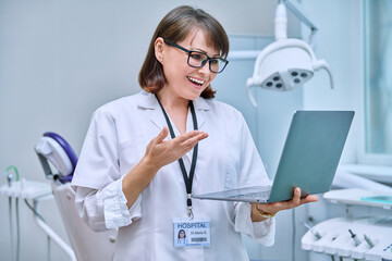 Doctor dentist working in office, using laptop, making video call conference