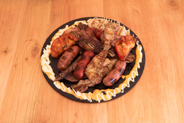 A circular tray of assorted roast meat with chorizos, Creole chorizos, strips of meat and ribs and...