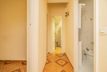 Distributor corridor of a vintage house with orange floors and access to the kitchen and toilet