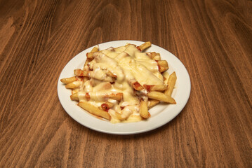 a portion of French fries with lots of melted cheese with fried bacon and ketchup