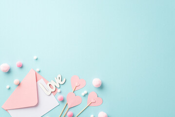 Valentine's Day concept. Top view photo of pink envelope with letter paper hearts on sticks inscription love and fluffy pompons on isolated pastel blue background with copyspace © ActionGP