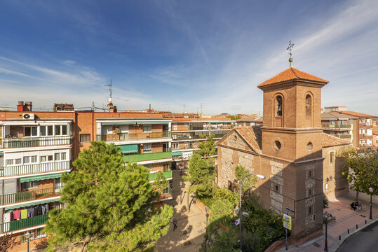A neighborhood church with a clay brick bell tower between the buildings and surrounded by trees