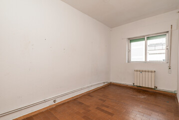 Empty living room with ugly brown tile floors, exposed heating pipes and white aluminum radiators