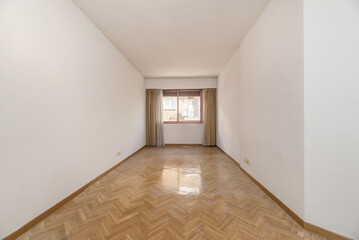 Empty living room with scarred oak parquet floor and bay window with curtains