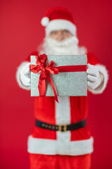 
Portrait von einem verkleideten Weihnachtsmann mit Geschenk, isoliert auf roten Hintergrund im Studio