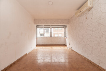 An empty room with an integrated terrace with an aluminum window and old ceramic tile floors