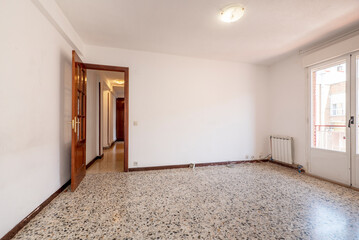 An empty room with access to others with wooden doors leading to a terrace and terrazzo flooring