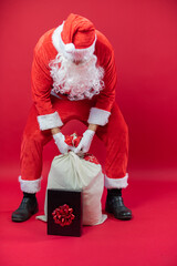 Portrait von einem verkleideten Weihnachtsmann, der auf einem Weihnachtsmarkt von Lichtern umgeben...