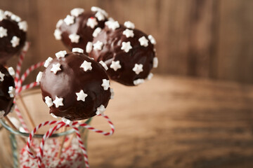 Marry Christmas sweet cake pops. Christmas dessert round brownie cake pops with stars topping on dark green background. Christmas food dessert concept and scene wide screen holiday border. Top view