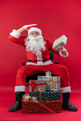 
Portrait von einem verkleideten Weihnachtsmann mit Geschenk, isoliert auf roten Hintergrund im...