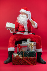 Portrait von einem verkleideten Weihnachtsmann mit Geschenk, isoliert auf roten Hintergrund im...