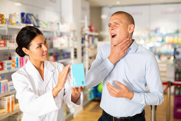 Man complains to a female pharmacist about a sore throat. Help in choosing a medicine in a pharmacy