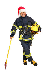 Full body young African-American fireman in fire-proof uniform and red santa hat, holds axe and yellow hard hat in hands over white background isolated.